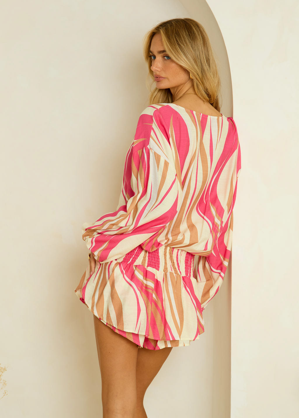 Woman wearing a pink and beige patterned dress against a plain background